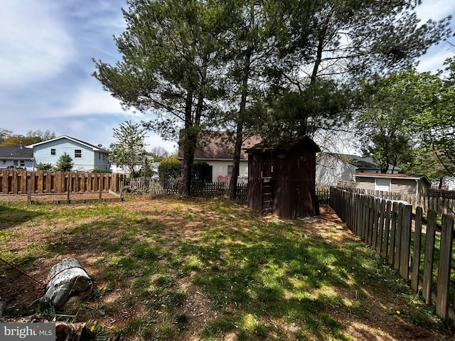 view of yard with a fenced backyard, a storage unit, and an outdoor structure