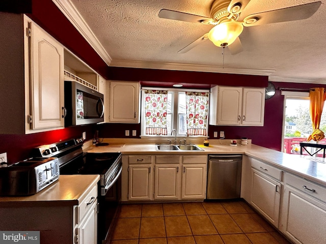 kitchen with crown molding, a sink, a textured ceiling, light countertops, and appliances with stainless steel finishes
