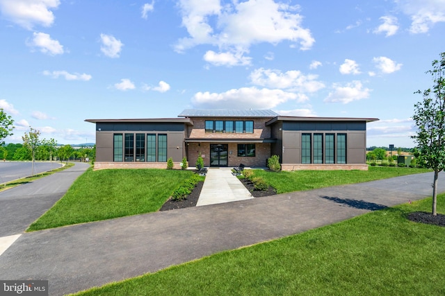 prairie-style house featuring french doors, stucco siding, brick siding, and a front yard