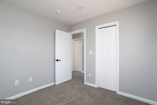 unfurnished bedroom featuring baseboards, carpet floors, and a closet