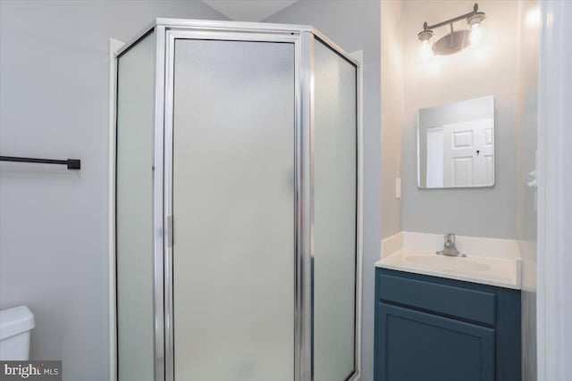 full bath with a stall shower, toilet, and vanity