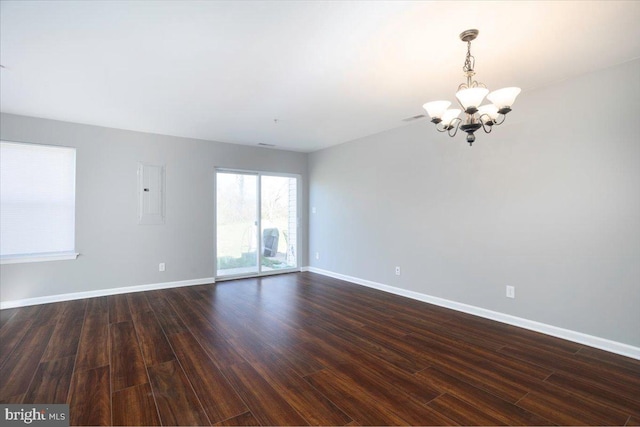 empty room featuring dark wood-type flooring, visible vents, baseboards, and a notable chandelier