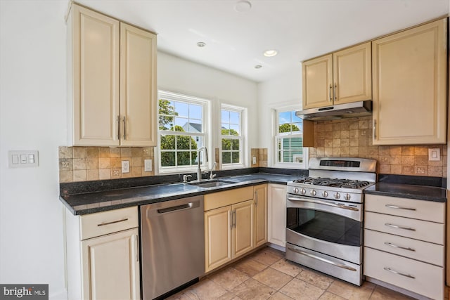 19916 Westerly Ave, Poolesville, MD 20837 - kitchen featuring appliances with stainless steel finishes, under cabinet range hood, cream cabinetry, dark countertops, and backsplash