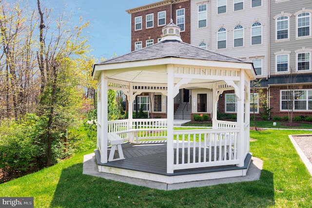 rear view of house featuring a gazebo, a yard, and a shingled roof