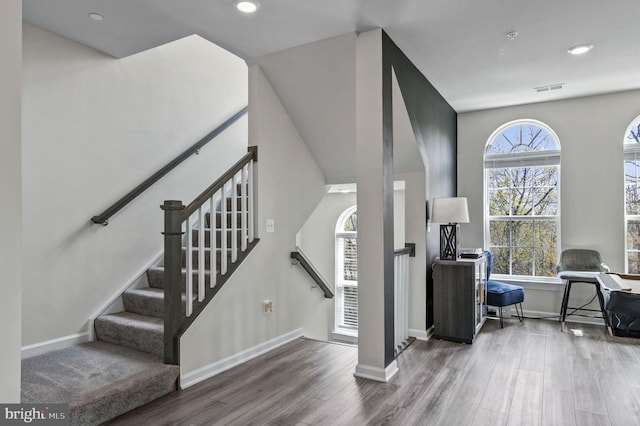 stairway featuring recessed lighting, wood finished floors, visible vents, and baseboards