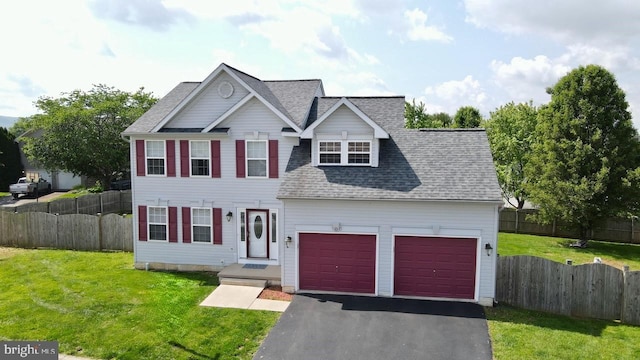 view of front of house with roof with shingles, driveway, fence, and a front lawn