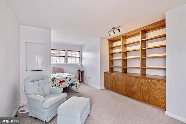 bedroom with light colored carpet, track lighting, and baseboards