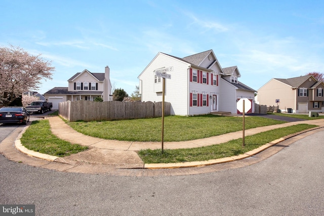view of property exterior with aphalt driveway, fence, a garage, and a lawn