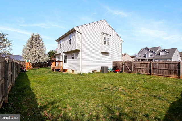 rear view of property featuring a fenced backyard, cooling unit, and a yard