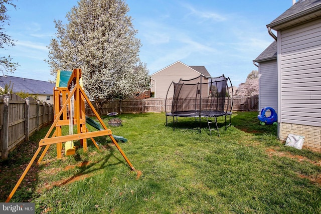view of yard featuring a trampoline, a playground, and a fenced backyard