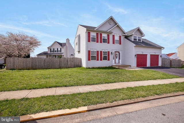 traditional-style house with a front yard, aphalt driveway, and fence