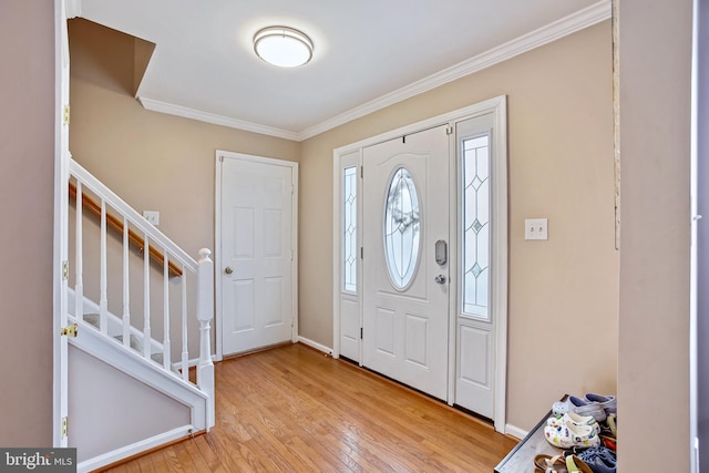 foyer entrance with wood-type flooring, ornamental molding, baseboards, and stairs