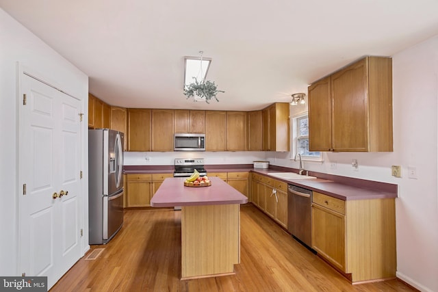 kitchen with a sink, stainless steel appliances, a center island, and light wood-type flooring