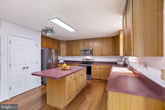 kitchen with a kitchen island, a sink, stainless steel appliances, and wood finished floors