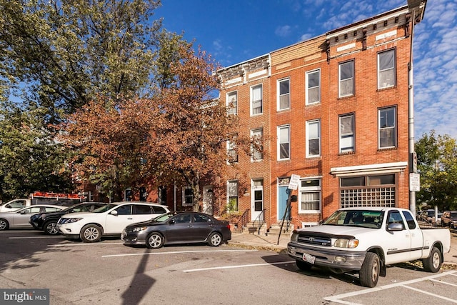 view of building exterior with uncovered parking and entry steps