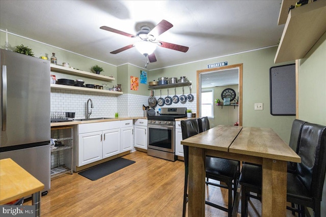 kitchen featuring white cabinets, open shelves, a sink, appliances with stainless steel finishes, and decorative backsplash