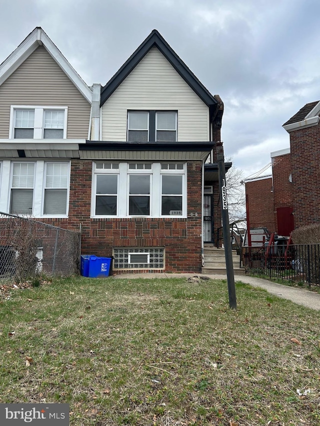 view of front of home with brick siding, fence, and a front yard
