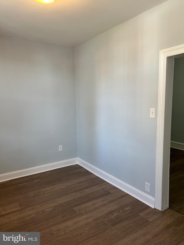 empty room with dark wood-type flooring and baseboards