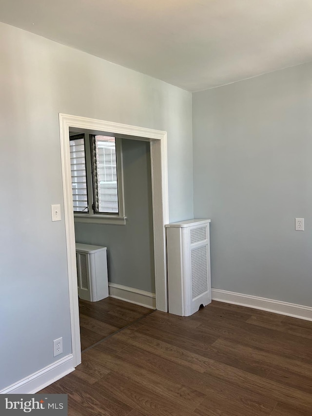 empty room featuring baseboards and dark wood finished floors