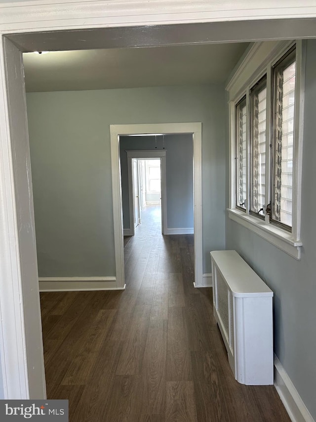hallway with dark wood finished floors and baseboards