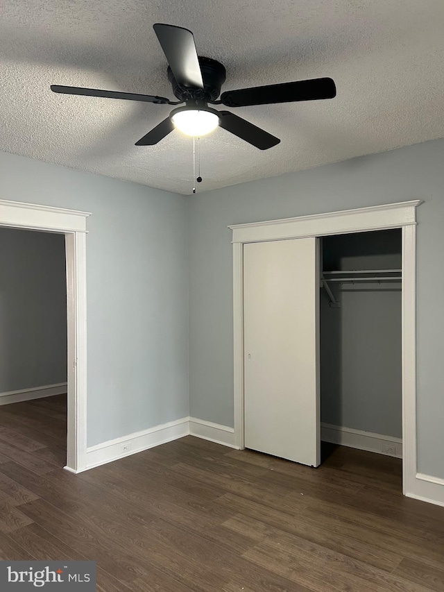 unfurnished bedroom with baseboards, a closet, dark wood-type flooring, and a ceiling fan