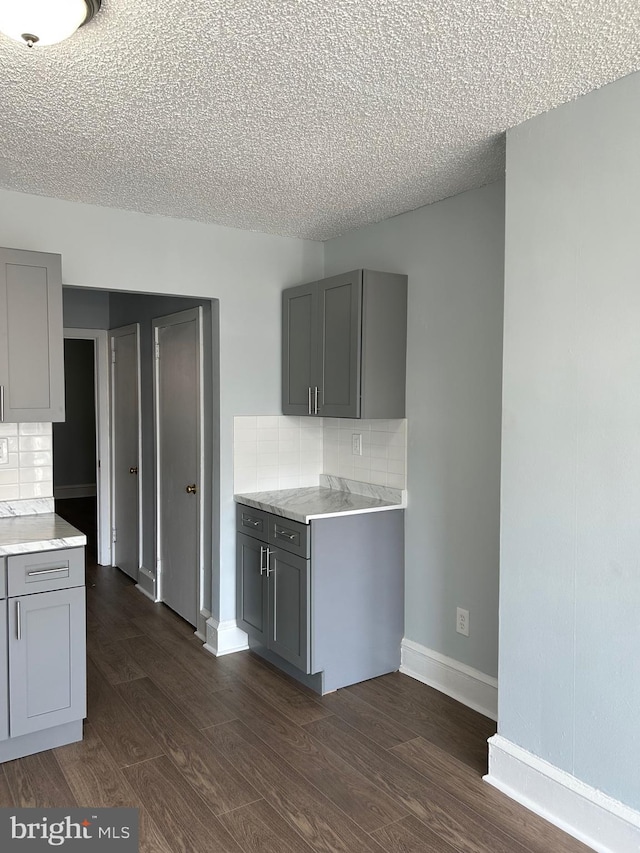 kitchen with light countertops, baseboards, gray cabinetry, and dark wood finished floors