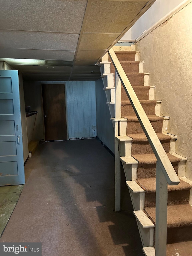 finished basement with stairs and a paneled ceiling