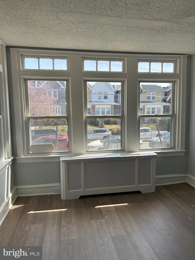 interior space featuring dark wood-type flooring, a wealth of natural light, and radiator heating unit