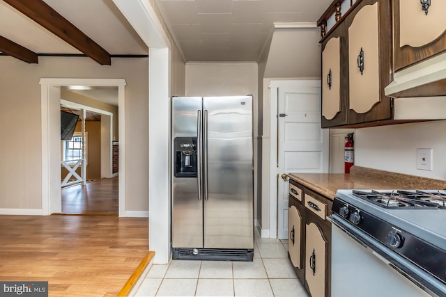 kitchen with light wood-style flooring, dark countertops, beam ceiling, stainless steel refrigerator with ice dispenser, and gas range oven