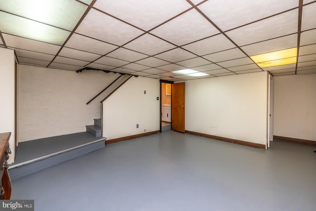 finished below grade area featuring baseboards, stairs, and a paneled ceiling
