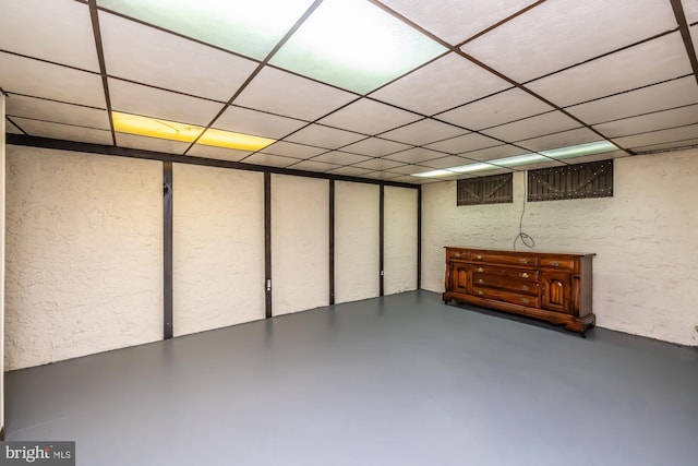 finished basement featuring a textured wall and a paneled ceiling