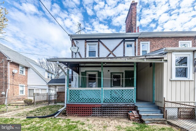 view of front of house with covered porch, fence, and a chimney