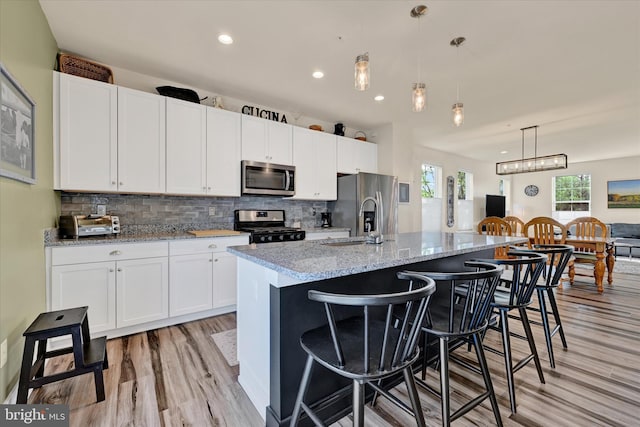 10031 Whitaker Way, Parkville, MD 21234 - kitchen featuring light wood-type flooring, a sink, white cabinets, stainless steel appliances, and an island with sink