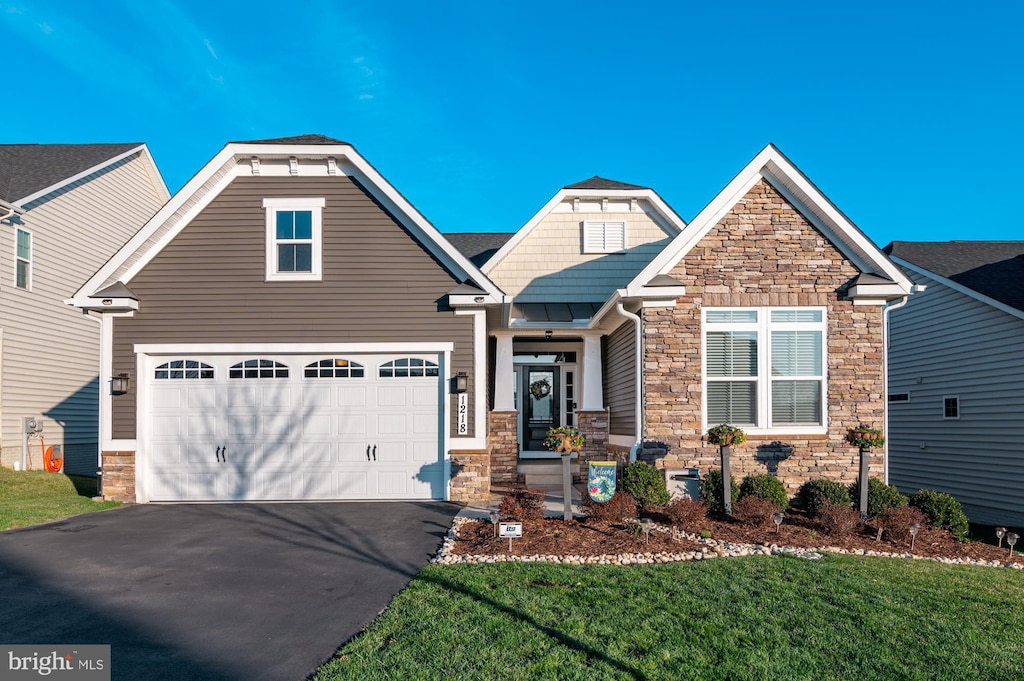 craftsman-style home with a front lawn, stone siding, and aphalt driveway