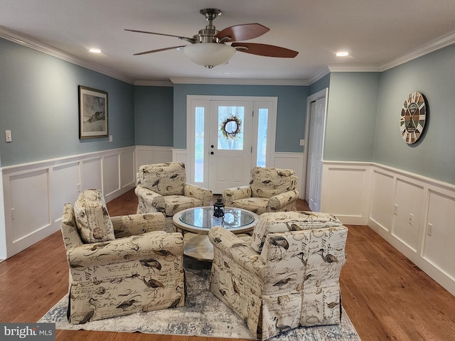living room with crown molding, a wainscoted wall, and ceiling fan