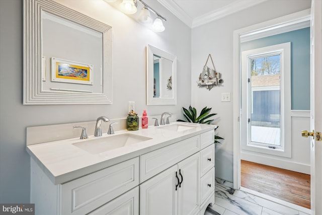 bathroom with marble finish floor, crown molding, a sink, and double vanity