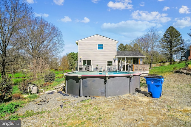 rear view of house featuring an outdoor pool and fence
