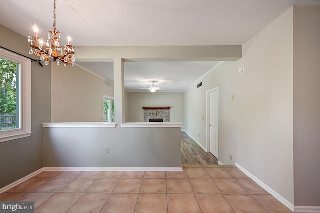 empty room featuring baseboards, visible vents, ceiling fan with notable chandelier, and a fireplace