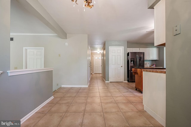hallway featuring baseboards, an inviting chandelier, and light tile patterned floors