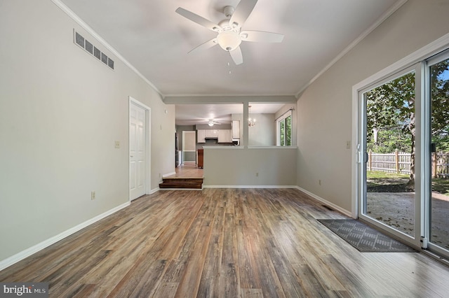 unfurnished living room featuring a ceiling fan, baseboards, wood finished floors, visible vents, and ornamental molding