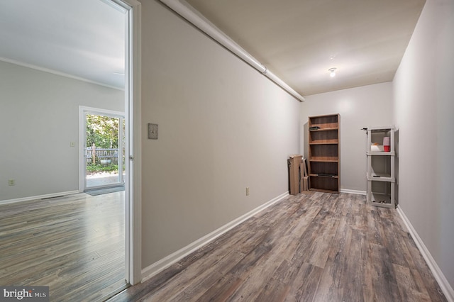hall featuring baseboards, ornamental molding, and wood finished floors