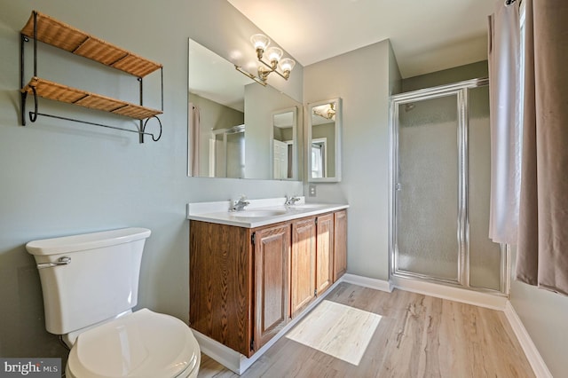 full bath featuring a sink, toilet, baseboards, wood finished floors, and a stall shower