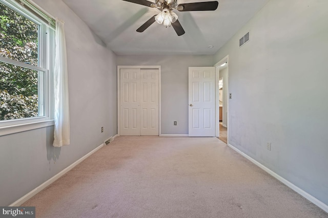 unfurnished bedroom with visible vents, multiple windows, and light carpet