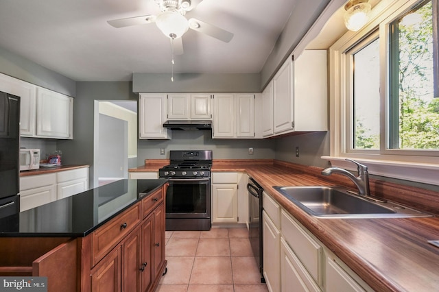kitchen featuring a sink, white cabinets, white microwave, range with gas stovetop, and under cabinet range hood