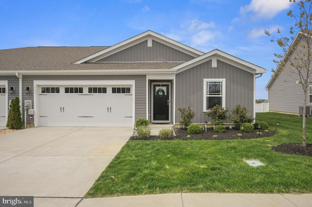 view of front of home with concrete driveway, a front yard, a shingled roof, and a garage