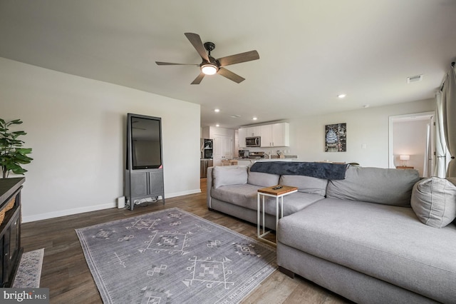 living area featuring dark wood-type flooring, visible vents, baseboards, and ceiling fan