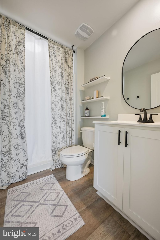 full bathroom with toilet, visible vents, wood finished floors, a shower with shower curtain, and vanity