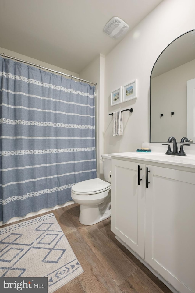 full bath with visible vents, wood finished floors, vanity, and toilet