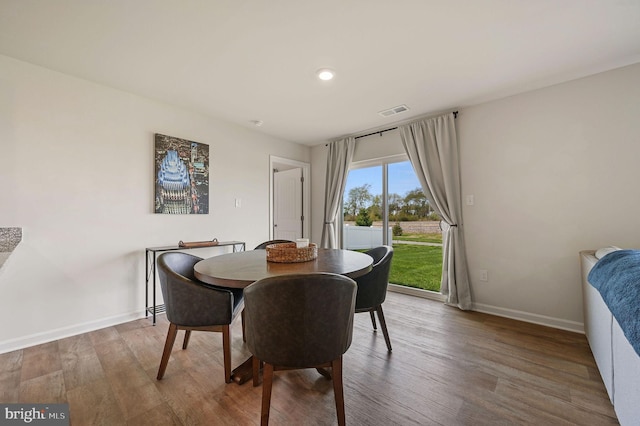 dining space featuring wood finished floors, visible vents, and baseboards