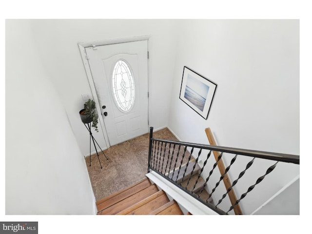 foyer featuring stairway, light colored carpet, and baseboards